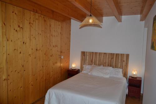 a bedroom with a white bed with wooden walls at Casa de Condeixinha in Condeixa a Nova
