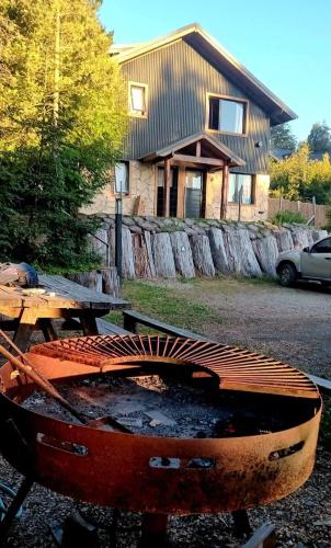 a wooden table and a grill in front of a house at Apu Wasi in Villa La Angostura