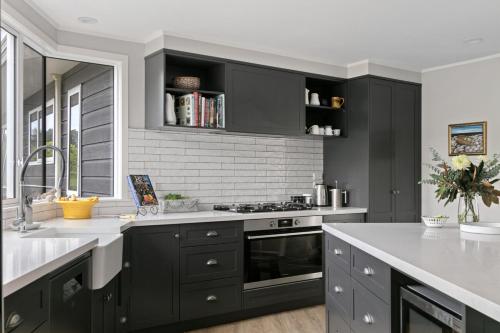 a kitchen with black cabinets and a stove top oven at NEW - Farm House Near Town! in Gisborne
