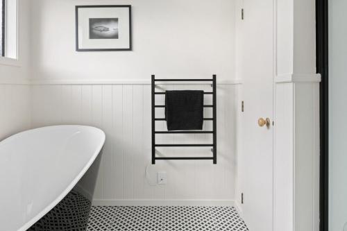 a white bathroom with a bath tub and a towel rack at NEW - Farm House Near Town! in Gisborne