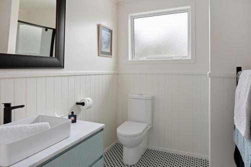 a bathroom with a toilet and a sink and a window at NEW - Farm House Near Town! in Gisborne