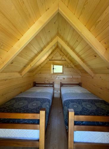 two beds in a log cabin with a window at Seosko domaćinstvo Desin Do in Berane