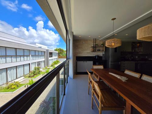 an open kitchen and dining room with a long wooden table at Ponta do Mutá Barra Grande 3 e 2 quartos pé na areia in Marau