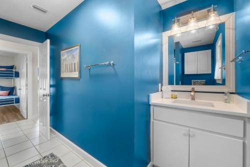 a blue bathroom with a sink and a mirror at Bonita Retreat in Panama City Beach