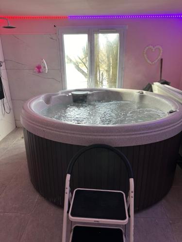 Cette chambre dispose d'un grand bain à remous et d'une chaise. dans l'établissement Bungalow 2 en bordure de lac accès jacuzzi, à Beaupouyet