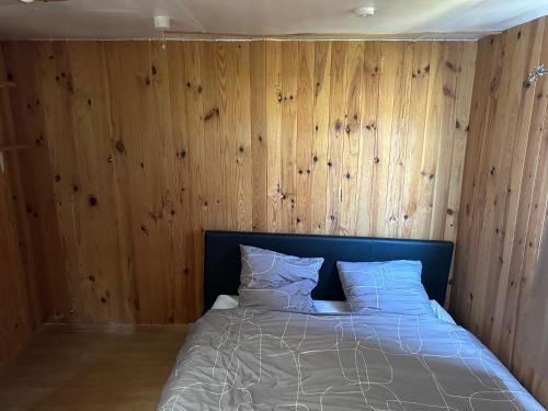 une chambre avec un lit avec des murs en panneaux de bois dans l'établissement Bungalow 2 en bordure de lac accès jacuzzi, à Beaupouyet