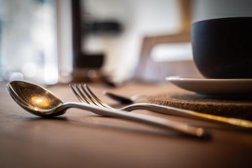 a wooden table with a spoon and fork and a cup at Alpine Mountain Chalet in San Vigilio Di Marebbe