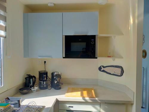 a kitchen with white cabinets and a microwave at Maison avec terrasses à 300m de la mer Juno Beach in Bernières-sur-Mer