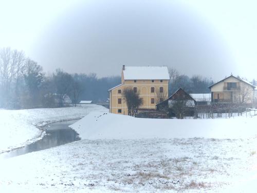 a house in the snow next to a river at Mill House Apartment and Camping in Ljutomer