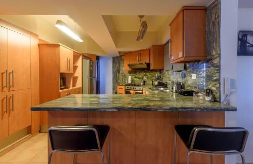 a kitchen with a counter with two chairs in it at Escape 3BR Apartment Close to Downtown Mall in Bella Vista in Santo Domingo