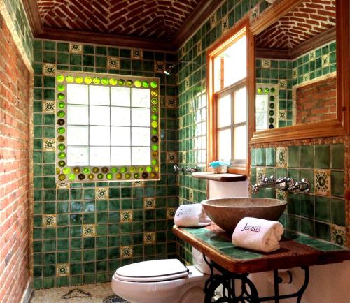 uma casa de banho com azulejos verdes, um WC e um lavatório. em Casa Jacinta Guest House em Cidade do México