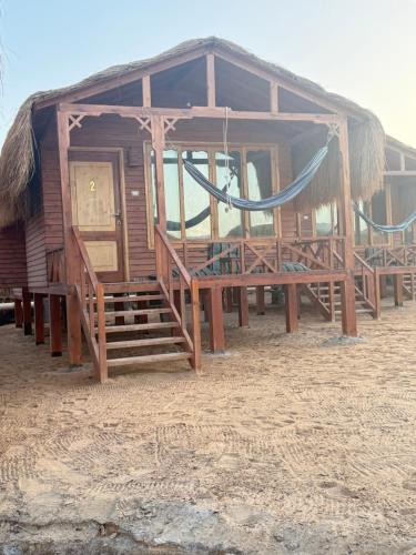 a wooden shack with a hammock on the beach at Love beach camp in Taba