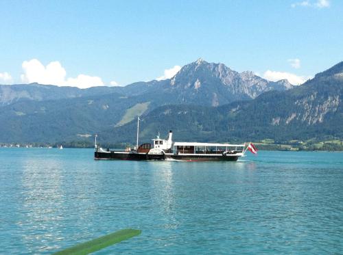 a boat on a lake with mountains in the background at Seehaus Familie Leifer in St. Wolfgang