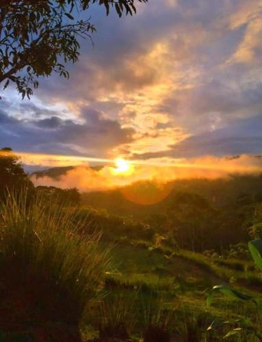a sunset over a field with the sun in the sky at Cabaña vista hermosa Matazanos in San Ramón Sur