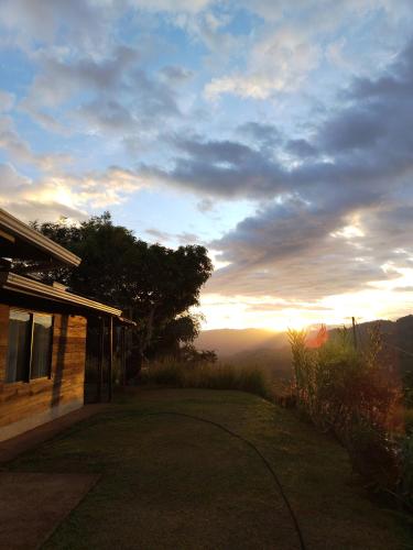 a view of a house with the sun setting in the distance at Cabaña vista hermosa Matazanos in San Ramón Sur