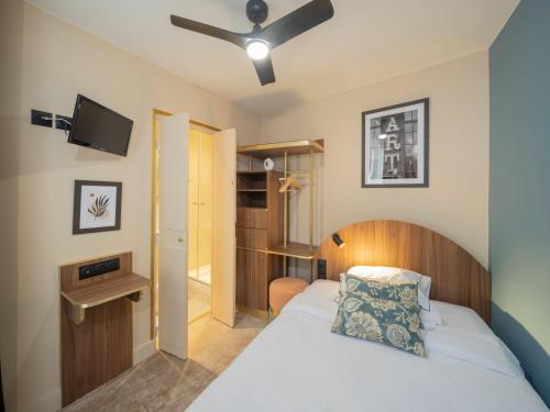 a bedroom with a bed and a ceiling fan at Hotel Boronali - Nouvellement rénové in Paris