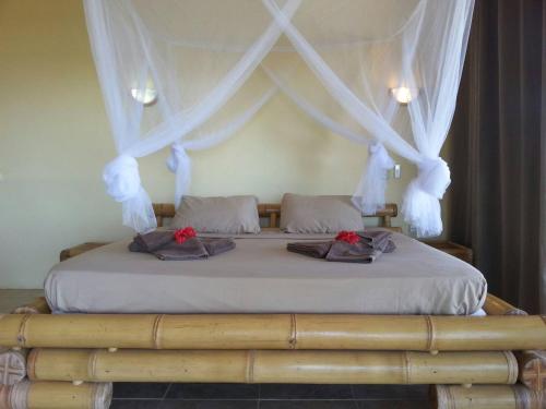 a bed with white curtains and red roses on it at Ocean Plateau in Motu Tiahura