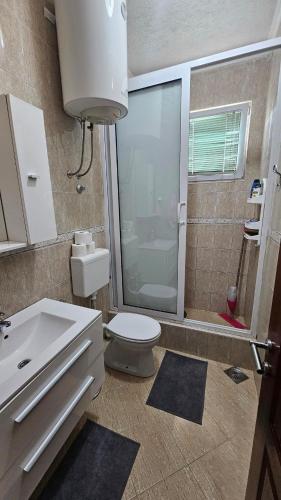 a bathroom with a toilet and a glass shower at Guest house Boljević in Rap