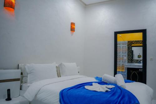 a bedroom with a bed with blue sheets and a mirror at RIAD REDWAN in Marrakech