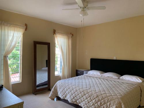 a bedroom with a bed with a ceiling fan and a mirror at Departamento completo, cómodo y cerca del aeropuerto in San Agustin de las Juntas