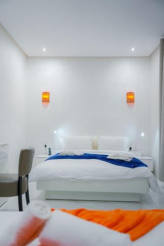 a white bedroom with a bed and a chair at RIAD REDWAN in Marrakech