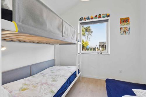 a bunk bed in a room with a window at Lovely Bright House Near The Beach In Nature in Ørsted