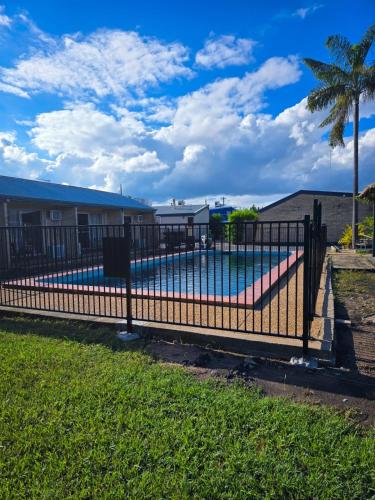 a fence around a swimming pool with a palm tree at Royal Motel Rockhampton in Rockhampton
