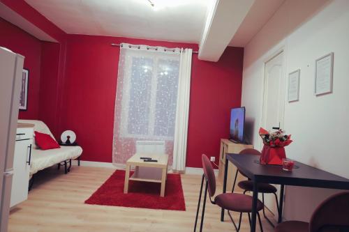 a living room with red walls and a table and a window at Château Rubis T2 hypercentre historique au pied du château in Château-Thierry