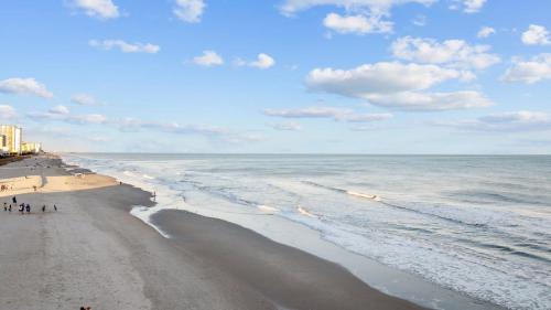 a beach with people walking on the sand and the ocean at Capers Blade - Across From Beach - Garage in Myrtle Beach