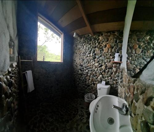 a stone bathroom with a sink and a window at Cacao Glamping in Cotundo