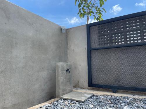 a concrete wall with a metal gate and a door at Lit-lit in Kangar