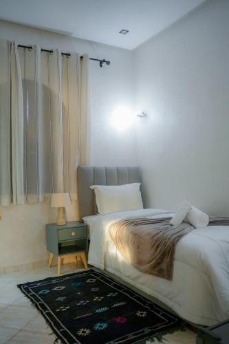 a bedroom with a bed and a table with a lamp at RIAD REDWAN in Marrakech