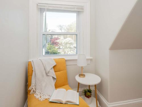 a room with a window and a chair with two books at Jennifer's Cozy Tower Lookout 3BR Brown U Views in Providence
