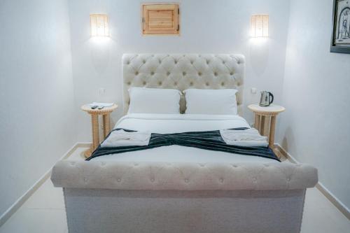 a white bed with a tufted headboard and two tables at RIAD REDWAN in Marrakech