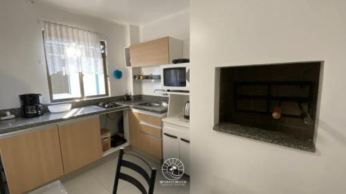 a kitchen with a large flat screen tv on a wall at Apto no centro de Torres | Aceita Pet in Torres