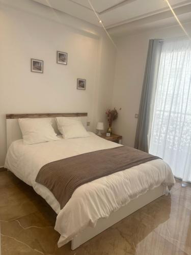 a bedroom with a large bed and a window at Joli appartement proche de la plage in Agadir