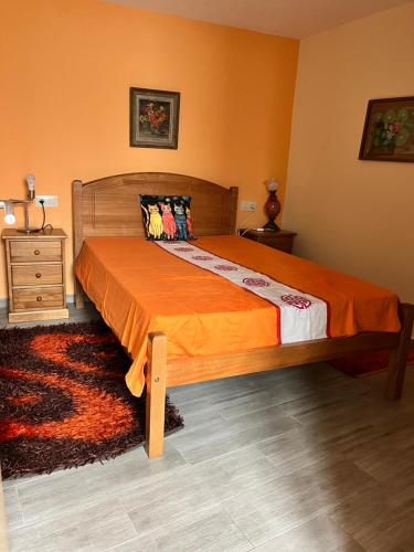 a bedroom with a large bed with an orange bedspread at Maison L aurore in Lobios