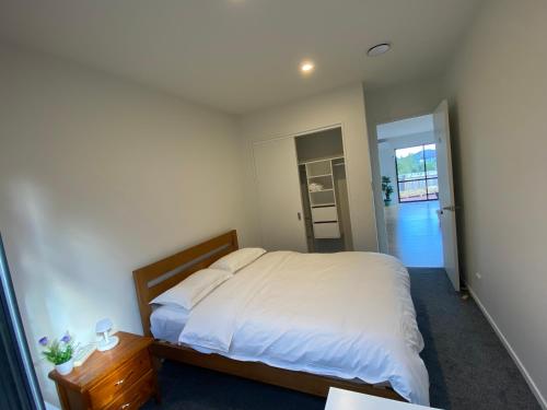 a bedroom with a bed and a door to a kitchen at CozyNest in Auckland