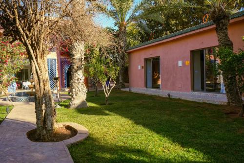 a yard with trees and a pink building at RIAD REDWAN in Marrakech