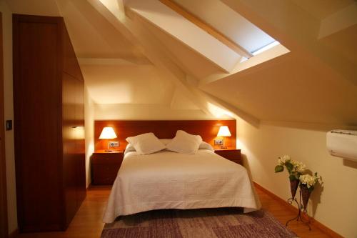 a bedroom with a bed with white sheets and a skylight at Hotel Casa de Caldelas in Castro Caldelas