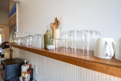 a shelf filled with glasses on a kitchen counter at Luxury Couples Stay Bangalow l Nova Escapes in Bangalow