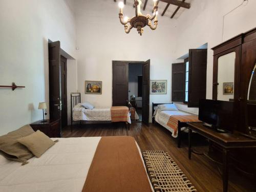 Un dormitorio con dos camas y un televisor y una lámpara de araña. en Casona de Epoca El Tatata, en San Lorenzo