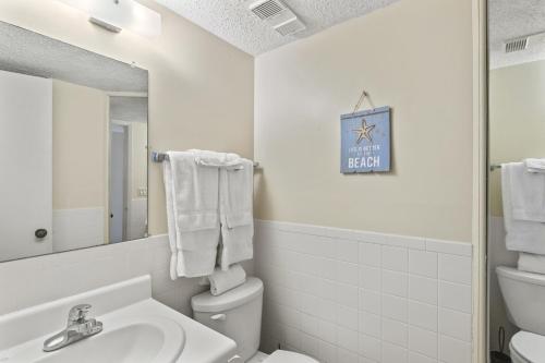 une salle de bains avec lavabo, toilettes et miroir dans l'établissement Pinnacle Port A-701, à Carillon Beach