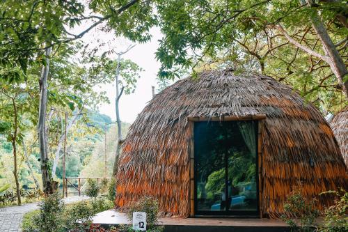 a small hut with a thatched roof at The Dome Hotel - Caylabne Bay in Ternate