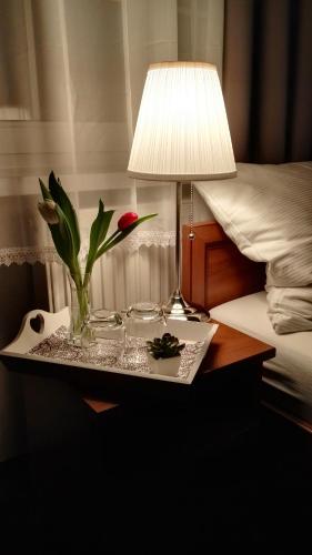 a table with a lamp and a vase with a flower at Pension Villa Marit in Prague