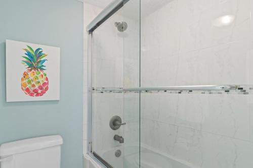 a bathroom with a shower with a pineapple painting on the wall at Pinnacle Port, A-708 in Carillon Beach