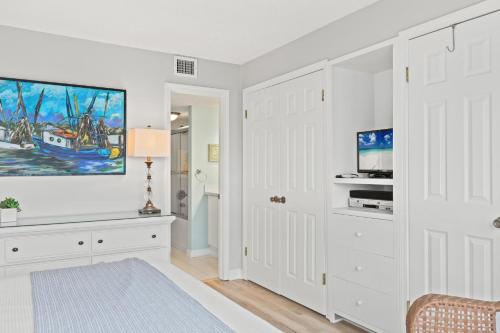 a living room with white walls and a tv at Pinnacle Port, A-708 in Carillon Beach