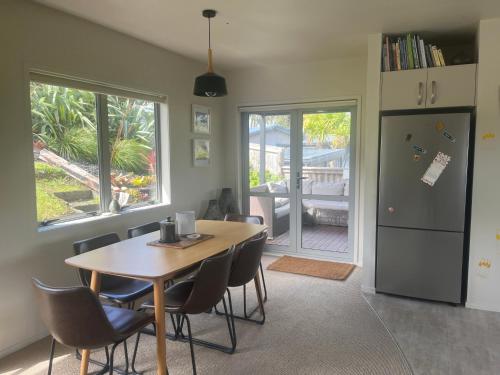 a dining room with a table and chairs and a refrigerator at RAGLAN - FULLY self contained 1 bedroom in Raglan