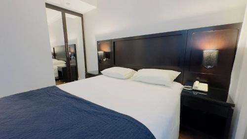 a bedroom with a large white bed and a mirror at HOTEL PERDIZES - FLAT Executivo - 1208 in Sao Paulo