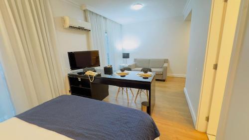 a room with a bed and a desk with a television at HOTEL PERDIZES - FLAT Executivo - 1208 in Sao Paulo